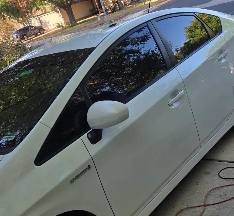 Close view of the windows and side mirror of a white Toyota.